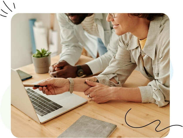 Un homme et une femme assis ensemble, concentrés sur un écran d’ordinateur portable.