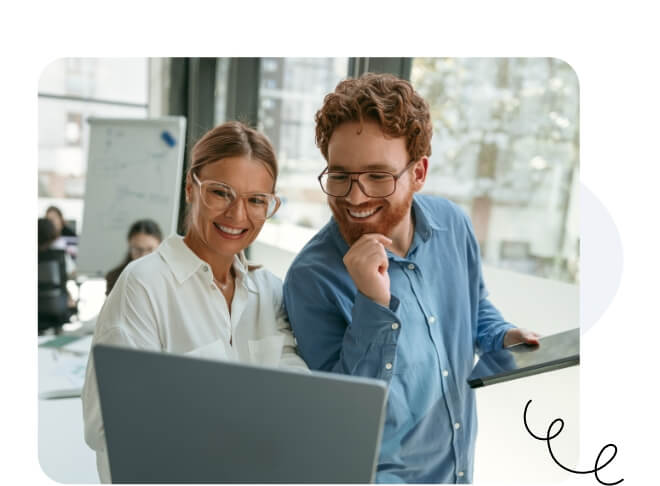 Un homme et une femme heureux avec des lunettes souriant devant le même ordinateur portable.