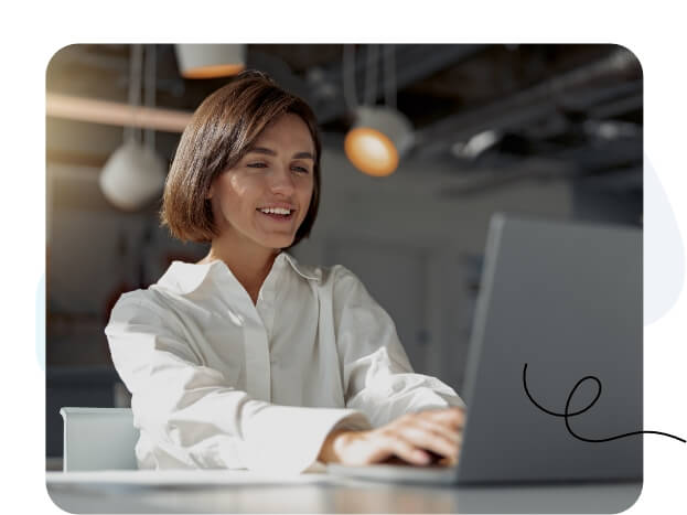 Une femme concentrée sur l’écran de son ordinateur portable dans un bureau moderne.